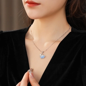 Detail of silver ginkgo leaf necklace with zircon crystal and white pearl on model