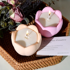 Vista cenital de velas de tulipán rosa y albaricoque en una cesta de mimbre rústica