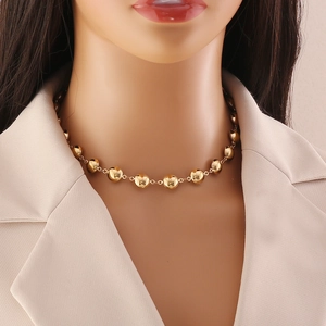 Polished gold beaded necklace with scallop heart design on a female model neck