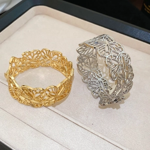 Detail of minimalist hollow butterfly cuff bracelet in gold and silver metallic finish