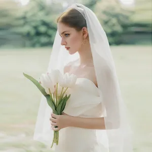 Elegant white long bridal veil in translucent tulle displayed by model in garden