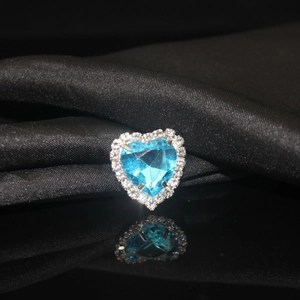 Macro detail of sky blue heart crystal pendant with claw-set stones on black silk