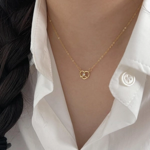 Close-up of heart-shaped gold necklace with zircon pendant worn by a female model