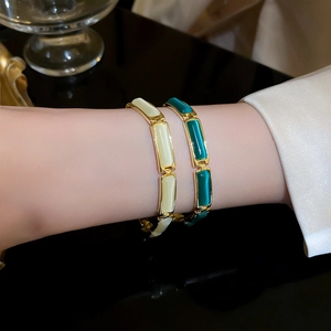 Detailed shot of gold plated bracelets with white and green cat eye stones on wrist