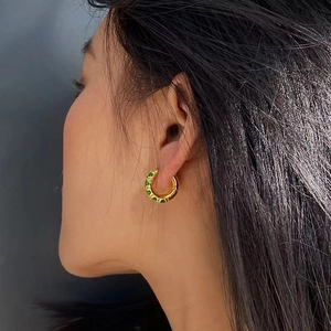 Elegant gold C-shaped geometric hoop earring featuring inlaid green zircon stones on model