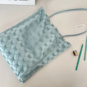 Détail du sac fourre-tout vert menthe avec matelassage en losanges et nœuds brodés