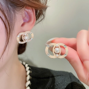 Detailed view of elegant gold stud earrings featuring interlaced rings and pearl accents