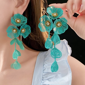 Vue détaillée des boucles d'oreilles fleurs en maille sarcelle avec étamines dorées et cristaux