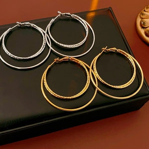 Detalle de pendientes de aro de doble capa en oro y plata sobre un soporte negro