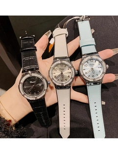 Three watches with rhinestones in black, white, and blue held in hand showing dial details