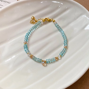Detail view of crystal beaded bracelet with blue and amber beads on a white tray