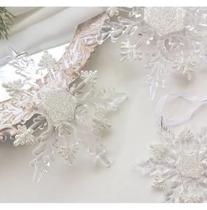 Detail of transparent acrylic snowflakes with silver glitter accents and white ribbon hanger