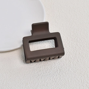 Macro shot of a matte brown rectangular hair claw clip on a clean textured white background