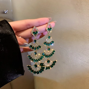 Detailed close-up of emerald drop fringe fan earrings with silver needles and rhinestones