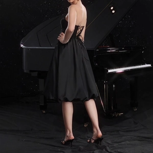 Detail of elegant black satin tube dress featuring a corset back and bubble hem silhouette