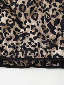 Detailed macro view of leopard print quilted fabric with neat black hem piping and stitching