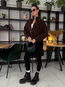 Details des dunkelbraunen Strickpullovers mit Reißverschluss und schwarzer Flecht-Handtasche