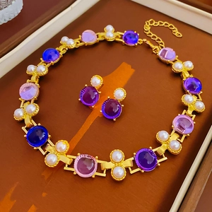 Détail de l'ensemble collier et boucles d'oreilles dorés avec perles et pierres mauves