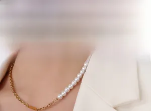 Détail d'un collier demi-chaîne dorée et demi-perles blanches porté sur un blazer beige