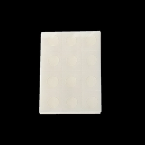 Detail view of 12 transparent adhesive glue dots for balloons on white liner paper