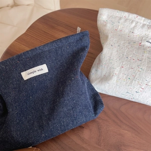 Close-up of retro denim and canvas makeup bags with simple wish woven labels on wood table