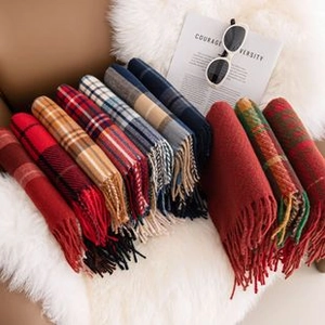 Close-up of rolled houndstooth and solid scarves with tassels on soft white plush rug