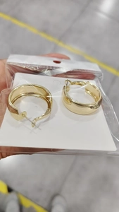 Close-up of golden wide-surface hoop earrings with simple white card packaging