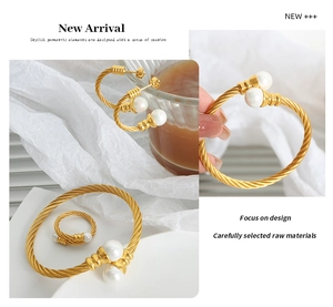 Detail of twisted gold metal jewelry set with white pearls including bangle and ring