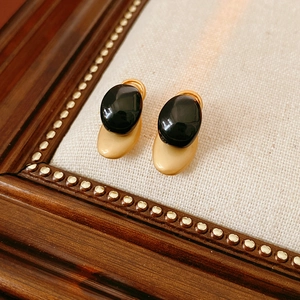 Macro shot of retro black oval resin earrings on a decorative vintage wooden frame