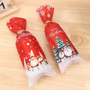 Festive red Christmas wine bottle covers with Santa prints on wooden background