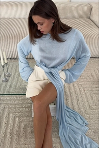 Dettaglio del top in maglia azzurro con lunghi nastri e pantaloncini bianchi alti