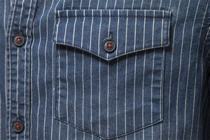 Close-up of heavy-duty washed striped denim shirt pocket with red stitching details