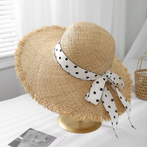 Chic raffia sun hat with frayed edge and polka dot ribbon on a display stand