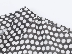 Detailed close-up of black and white polka dot chiffon fabric with precision stitching