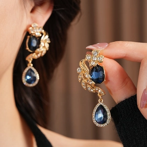 Détail de boucles d'oreilles vintage dorées avec cristaux bleu foncé en forme de gouttelette