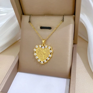 Macro view of gold Saint Benedict heart pendant with white zircon stones in jewelry box