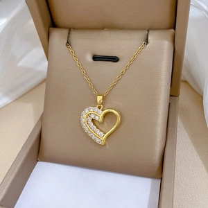 Détail d'un collier cœur doré à deux couches serti de zircons dans son écrin de luxe