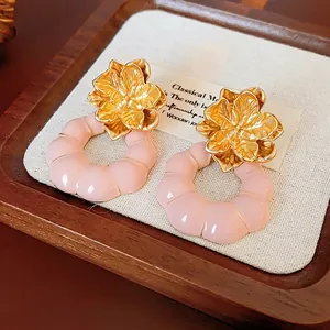 Vintage floral stud earrings with gold petals and pink ribbed circles on wooden tray