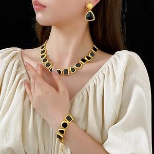 Detail of vintage geometric gold jewelry set with black enamel inlay on a model