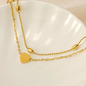 Detail of 18K gold stainless steel double-layered anklet with a delicate heart pendant