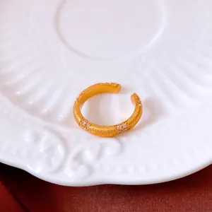Bague vintage dorée avec zircons et finition brossée sur soie rouge et porcelaine