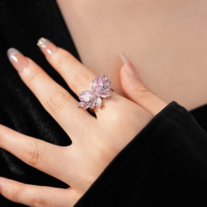 Gros plan d'une bague papillon en zircon rose portée sur un doigt