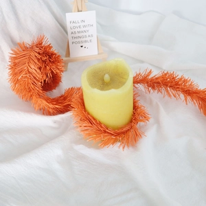 Close-up of orange tinsel garland and yellow LED candle for festive home decoration
