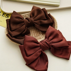 Detail of two-piece satin bow hair clips in dark brown and reddish brown colors