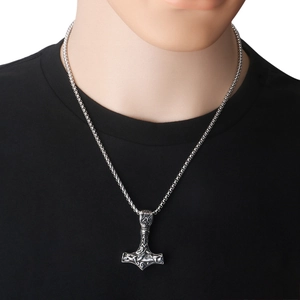 Detail of vintage silver Viking Mjolnir pendant with intricate patterns on a box chain
