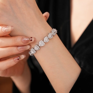 Macro detail of a sparkling silver heart bracelet with white zircon stones on a model wrist