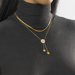 Detail of double-layer gold necklace with shell flower pendant on a black sweater