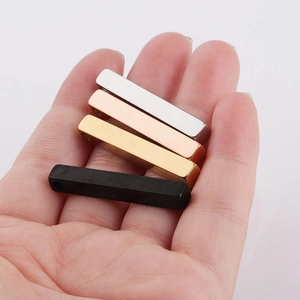 Detailed view of four vertical stainless steel bar pendants in silver, gold, rose gold, and black