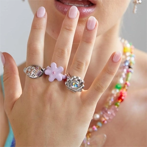 Conjunto de anillos de moda con estrellas plateadas y motivos florales lavanda en la mano