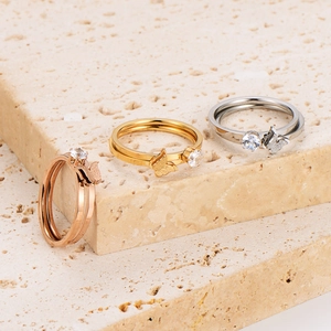 Stackable butterfly zircon rings in rose gold, gold and silver finishes on a stone surface